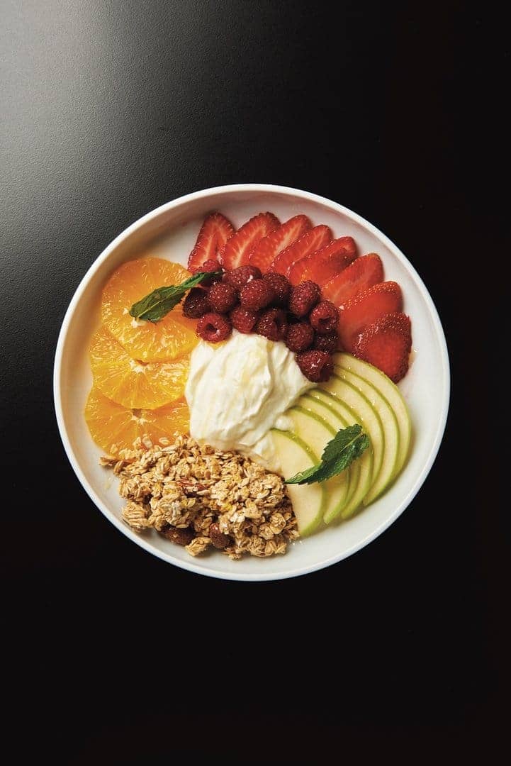 Bowl de yogur con frutillas, frambuesas, naranja, manzana verde y granola