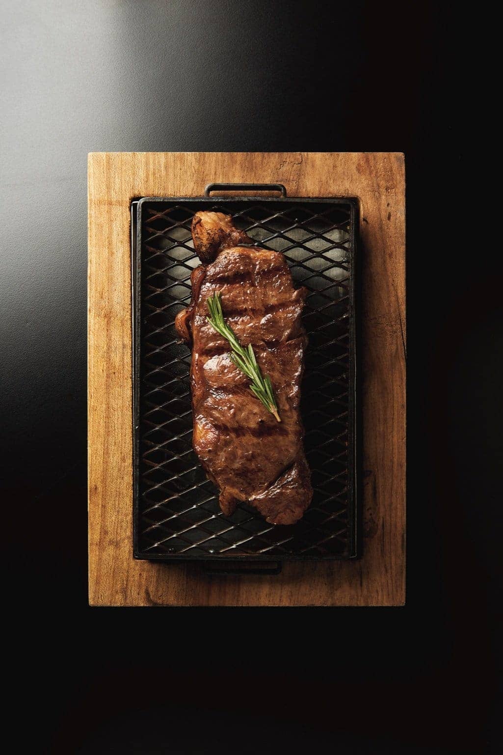 Bife a la parrilla con romero sobre una tabla de madera